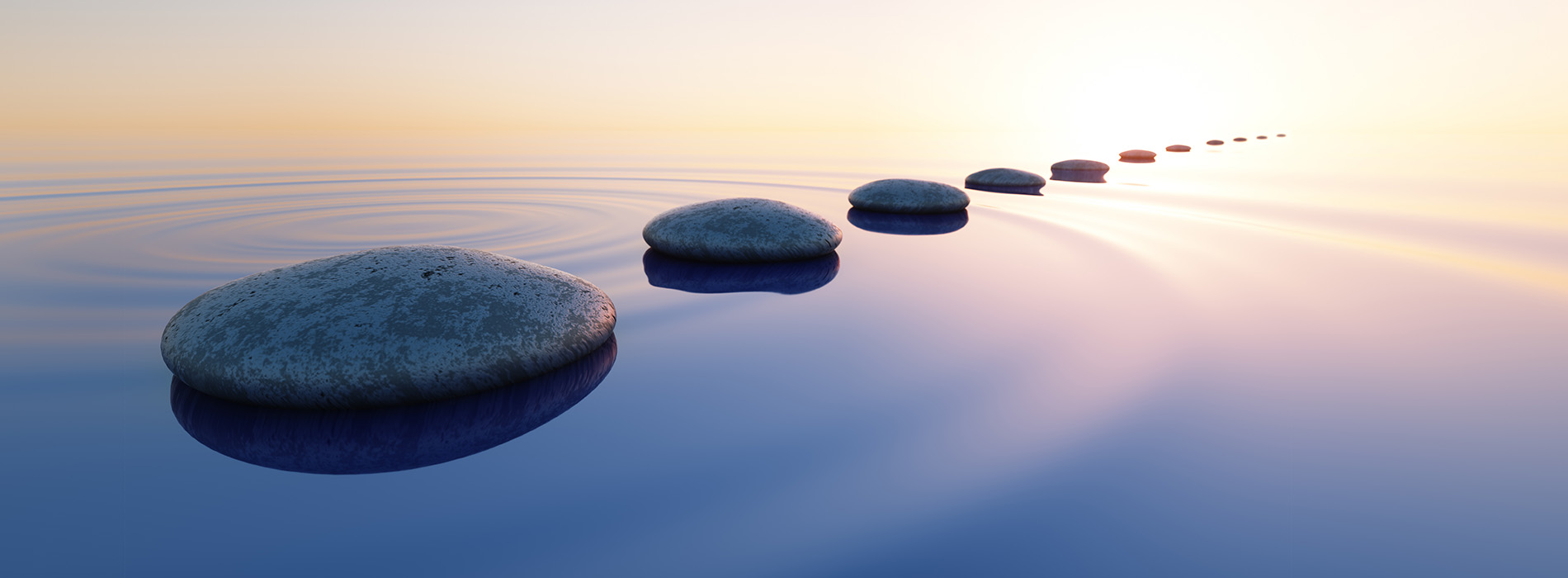 Three stones in a serene water setting, with a sunset backdrop.